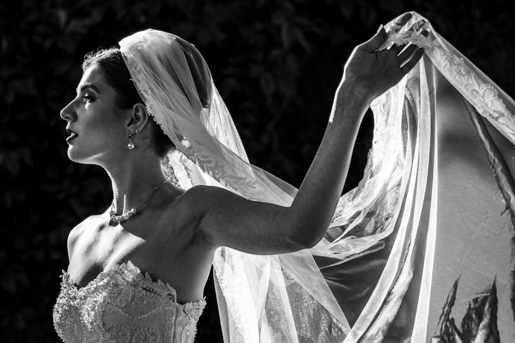 Una novia sosteniendo su velo con una iluminación dramática