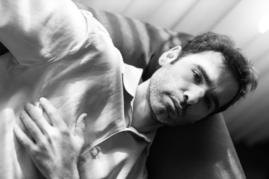 Retrato en blanco y negro de un hombre con camisa blanca sentado en un sofá
