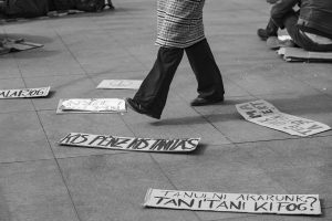 Piernas caminando entre pancartas de protesta en el suelo.