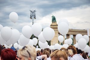 Personas en una manifestación sosteniendo cientos de globos blancos.