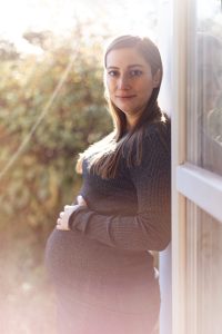 Retrato de maternidad de una mujer embarazada disfrutando del sol primaveral.
