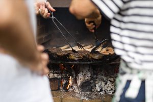 La parte trasera de madre e hijo haciendo una barbacoa en el jardín.