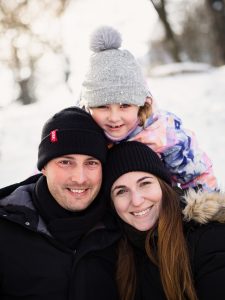 Un feliz retrato familiar de una madre, un padre y una hija en un paisaje nevado.